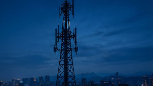 Torre de telecomunicaciones sobre la ciudad al anochecer